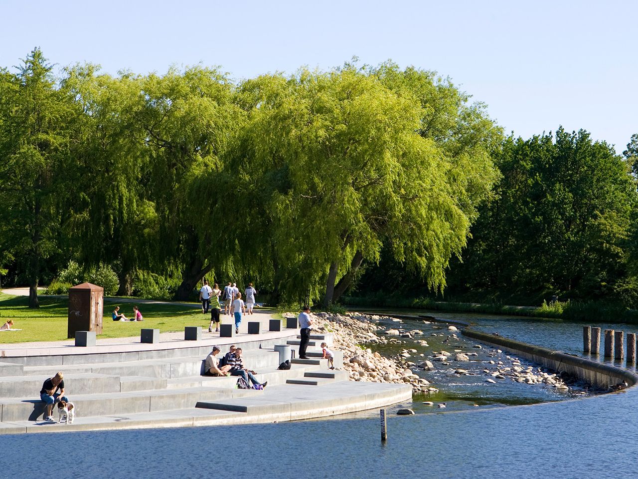Menschen sitzen in einem Park in Odense im Sonnenschein