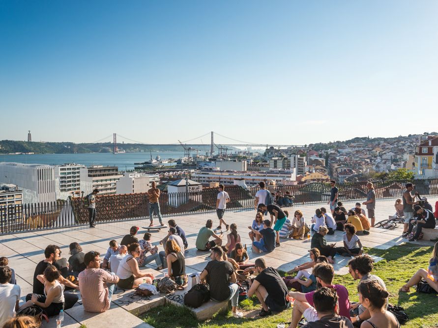 Menschen sitzen am Miradouro de Santa Catarina