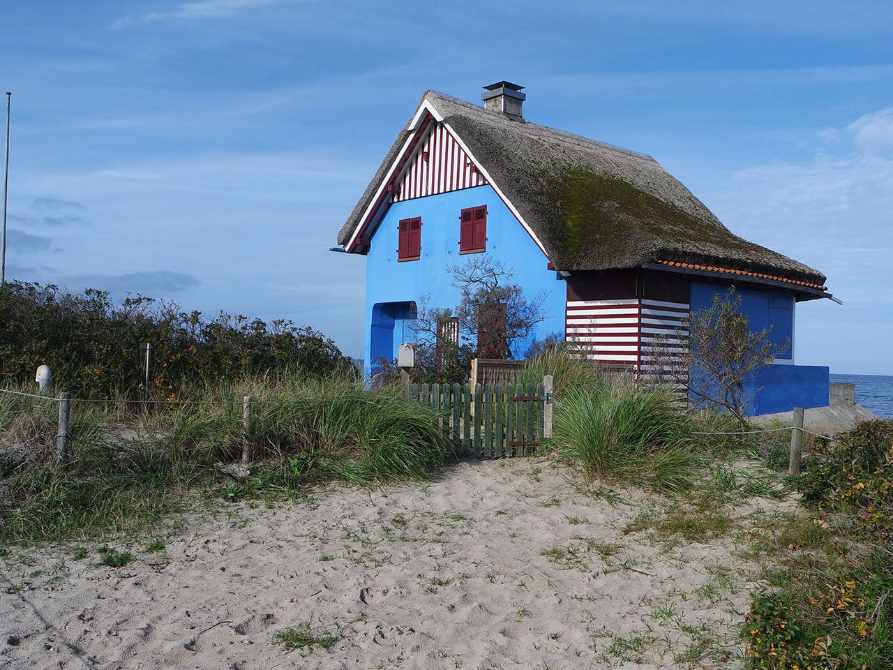 Blaues Haus mit Reetdach am Graswarder-Strand, Heiligenhafen (Ostsee)