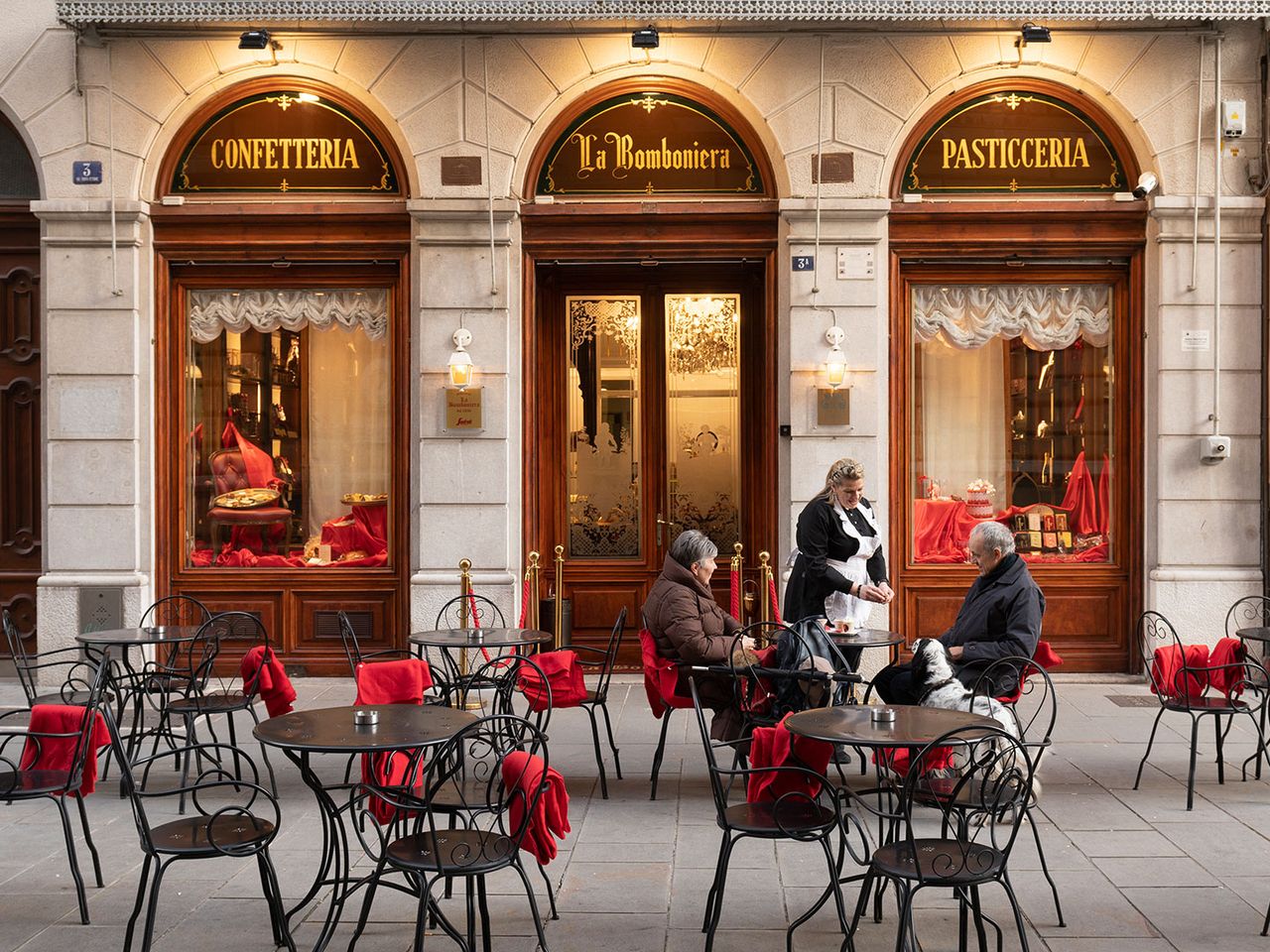 Menschen sitzen vor der Pasticceria La Bomboniera in Triest