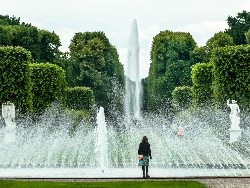 Eine Frau steht vor einer Fontäne im Großen Garten Hannover
