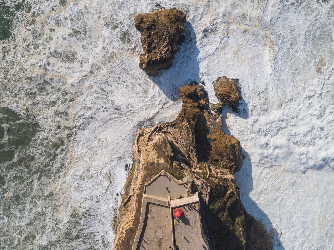 Wellen brechen sich an der Festung von Nazaré