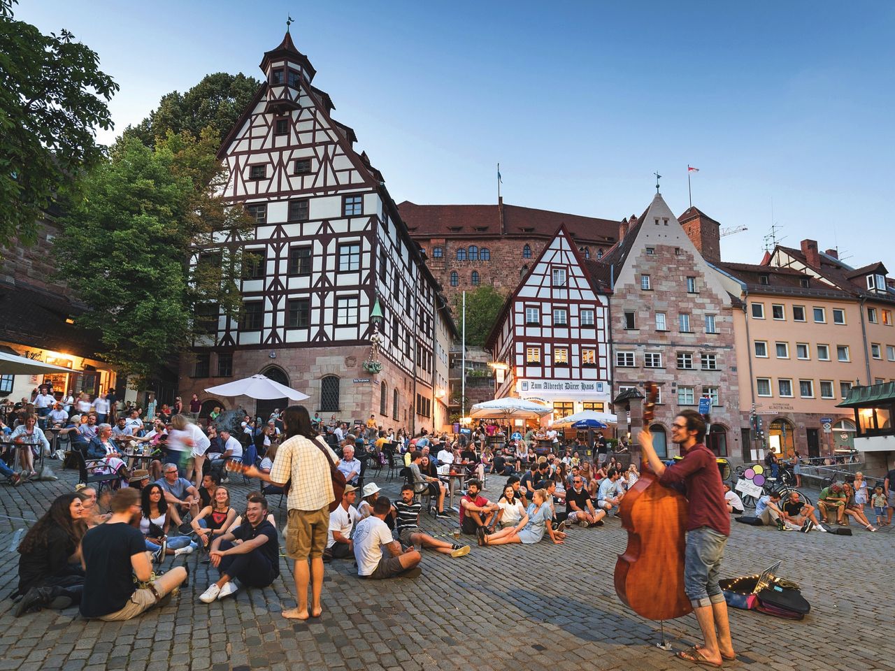 Menschen sitzen am Fuße der Nürnburger Burg