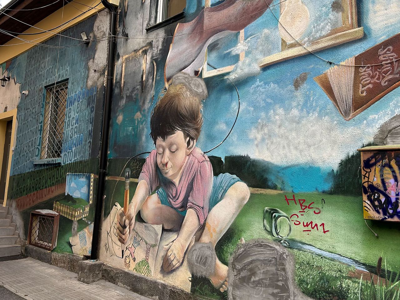 Street Art an einer Hauswand in Sofia, Junge zeichnet