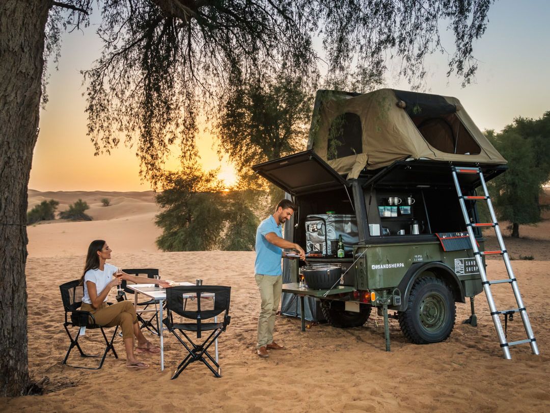 Camper bei ihrem Trailer im Sand Sherpa Desert Camp