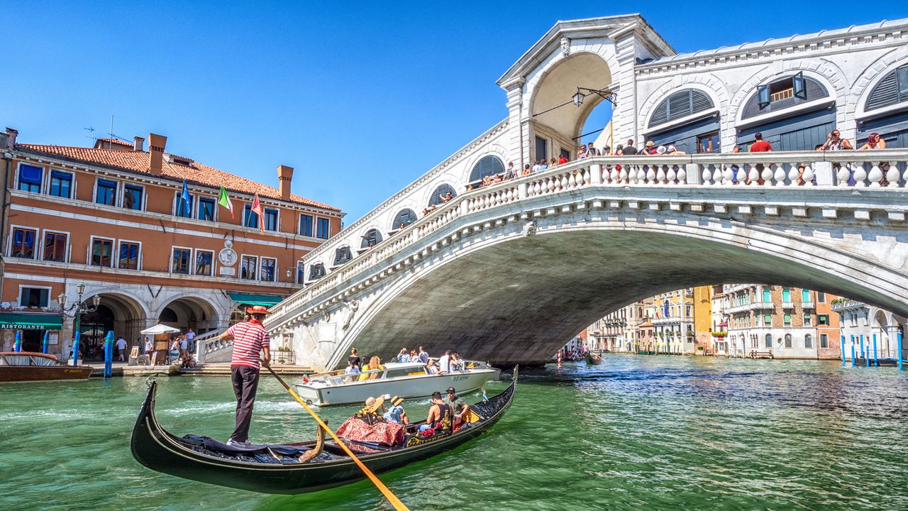 Eine Gondel fährt durch die Rialtobrücke in Venedig