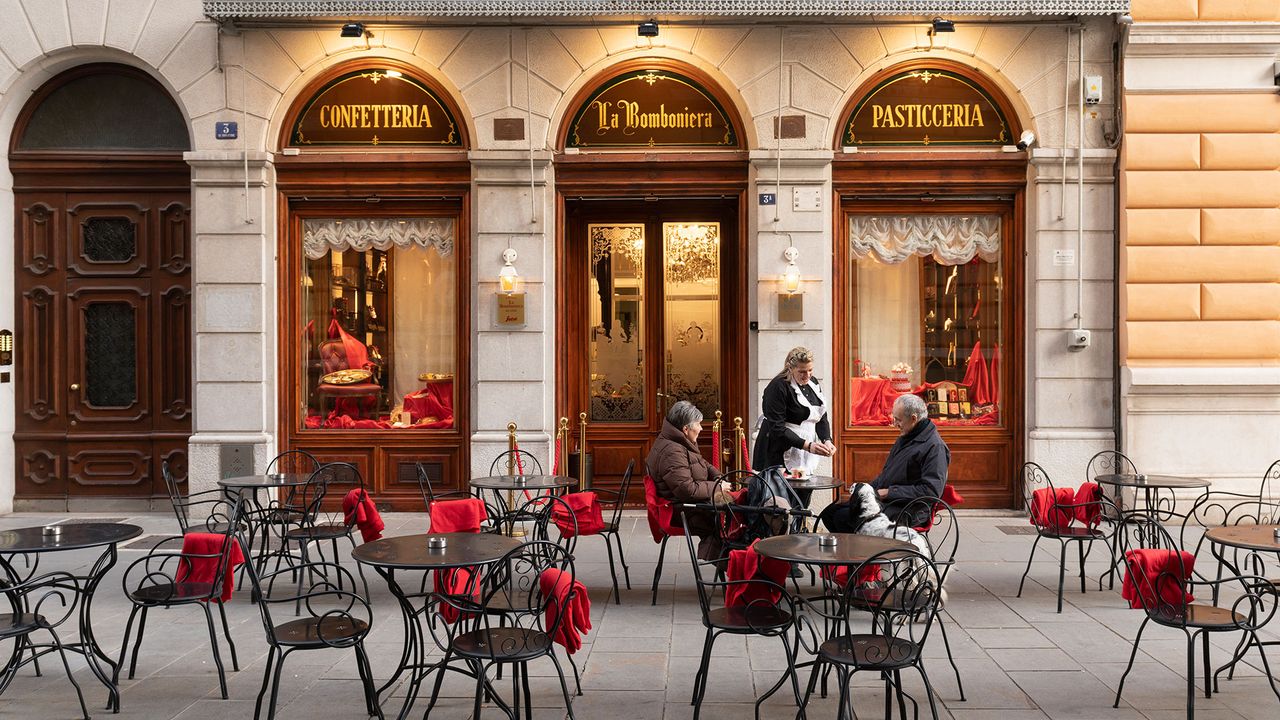 Menschen sitzen vor der Pasticceria La Bomboniera in Triest