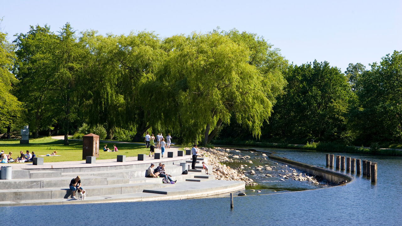 Menschen sitzen in einem Park in Odense im Sonnenschein