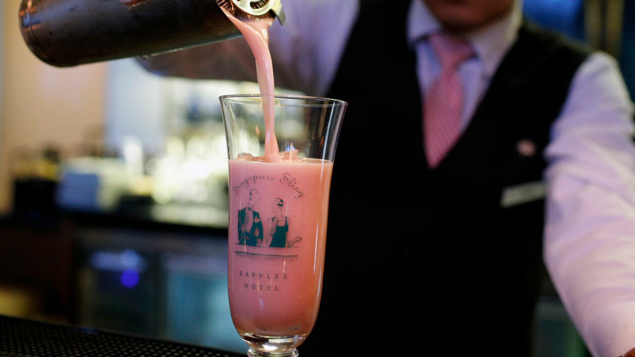 Ein Barkeeper im Raffles Hotel serviert einen Singapore Sling Cocktail