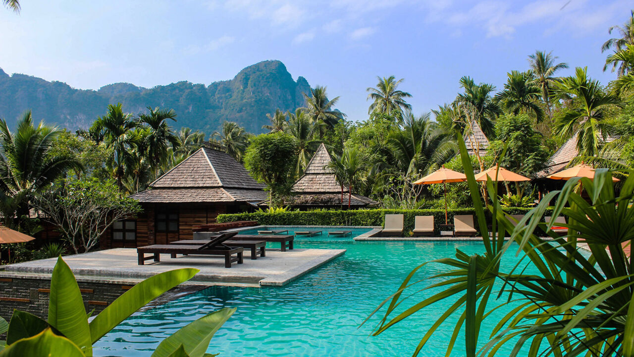 Bungalows stehen am türkisfarbenen Wasser in Thailand