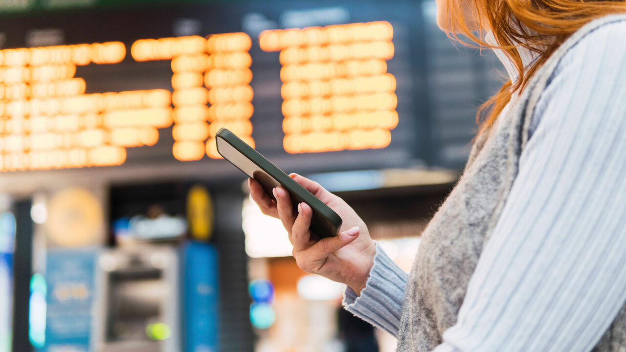 Eine Frau hält am Flughafen ein Smartphone in der Hand
