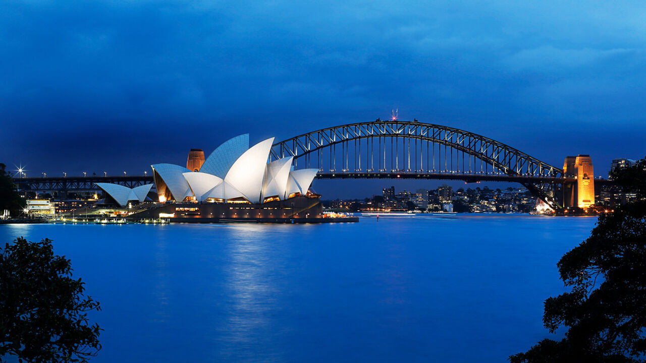 Der hell erleuchtete Hafen von Sydney mit Opernhaus.