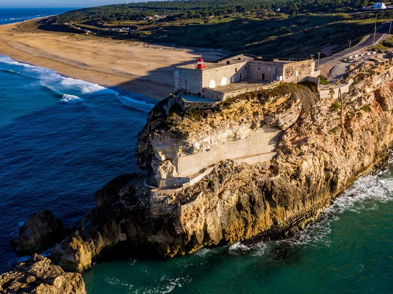 Nazaré ist berühmt geworden für seine meterhohen Wellen und perfekten Surfspots. Blick auf die Festung auf einer Klippe in Nazaré