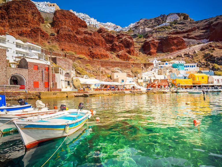 Die Bucht von Ammoudi und der gleichnamige Strand gehören zu den schönsten Orten auf Santorini Segelboote liegen vor der sonnenbeschienenen Bucht von Ammoudi