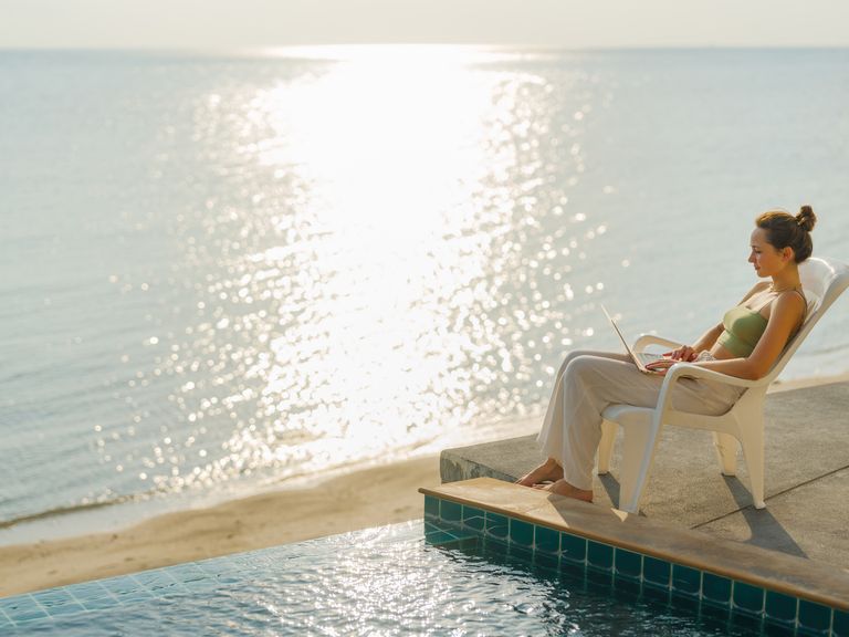 So lässt es sich arbeiten: Workation am Meer Workation, Frau sitzt mit Laptop am Pool