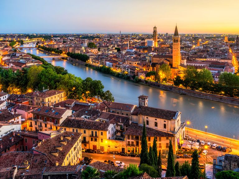 Die Etsch schlängelt sich durch Verona und bietet grandiose Fotomotive. Blick auf die Etsch und Verona von oben, am Abend, beleuchtet