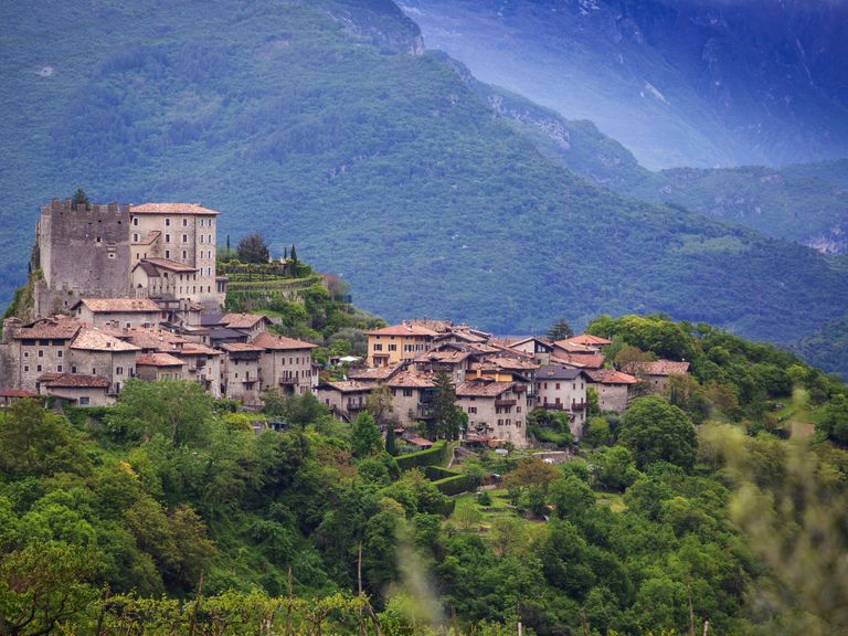 Seasons_13187688_HiRes_Blick_auf_das_Dorf_Tenno_in_der_Landschaft_des_waldreichen_Trentino_Italien