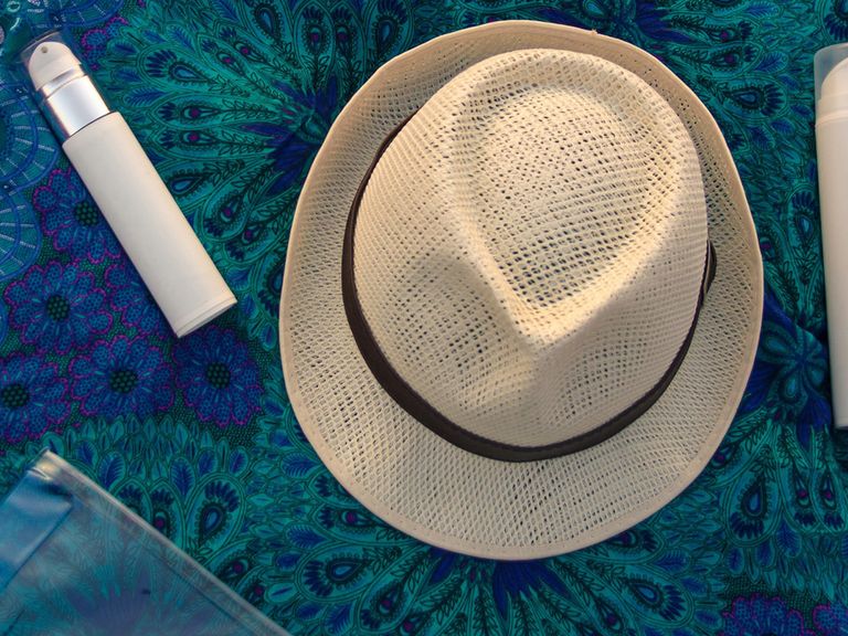 Wer Urlaub macht, fragt sich häufig, was alles in die Reiseapotheke gehört. Wir geben Hilfestellung. Hut und Cremes liegen auf einem Strandtuch