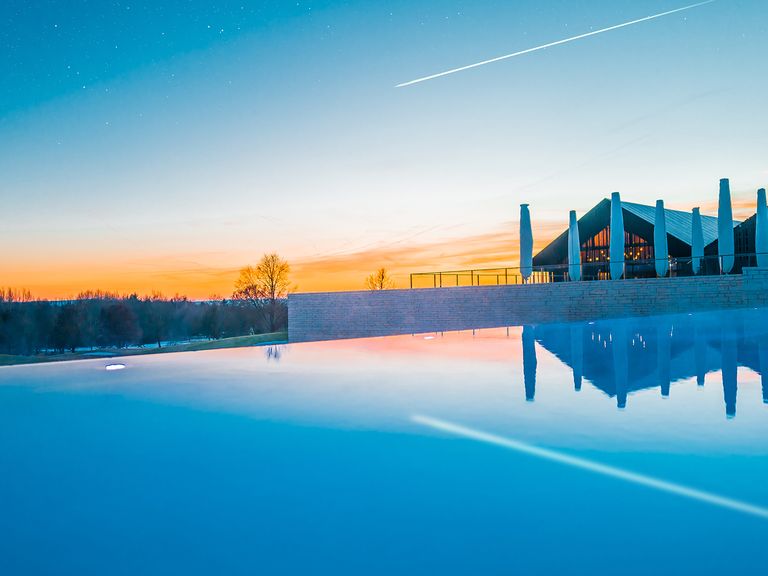 Im Öschberghof schwimmen Spa-Besucher:innen mit Blick auf den Schwarzwald. Infinity Pool im Öschberghof, Schwarzwald