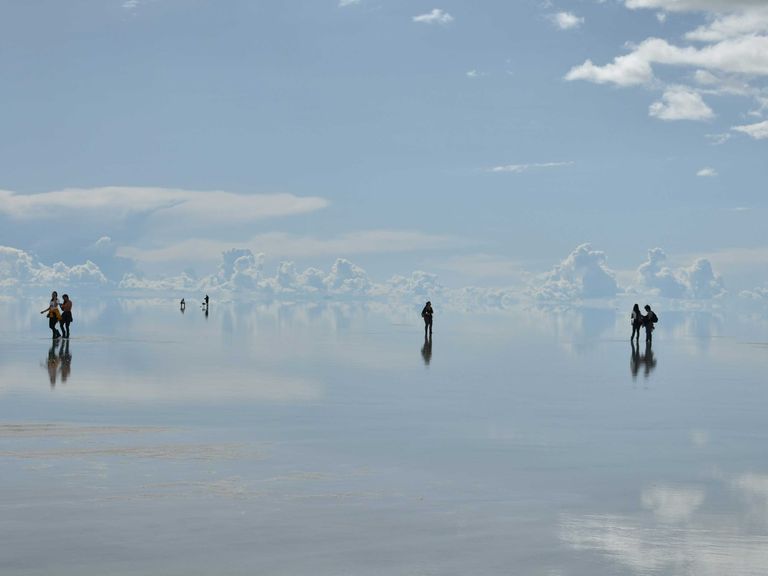 Wie ein „Cloud Dancer“ fühlt man sich auch in der Salar de Uyuni, der größten Salzfpanne der Welt in Bolivien. Menschen auf dem Salzsee der Salar de Uyuni, Bolivien
