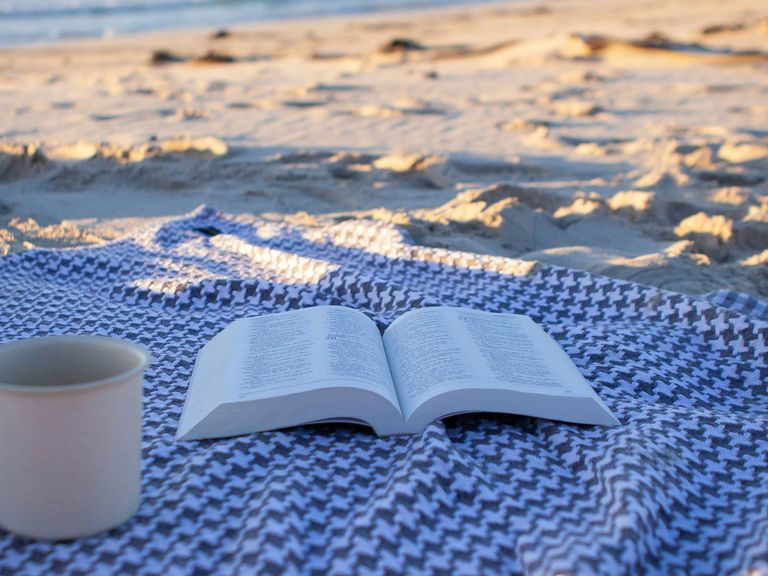 Buch und Kaffeetasse am Strand