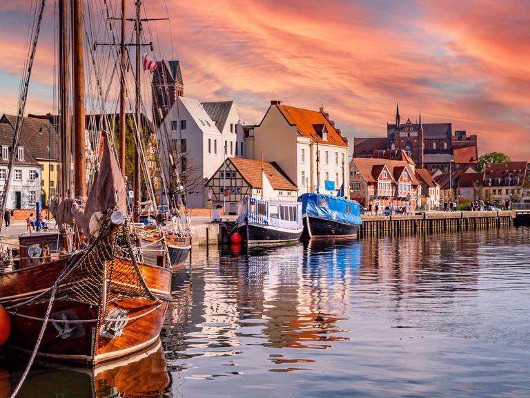 Rote Backsteingiebel in der Sonne, kreischende Möwen im Hafen, glitzernde Ostseewellen: Das alles ist Wismar. Alter Hafen in Wismar im Sonnenuntergang