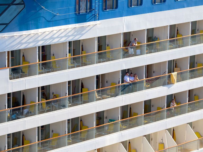 Menschen stehen auf den Balkonen eines Kreuzfahrtschiffs