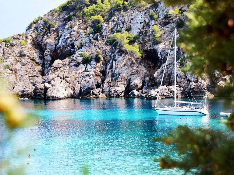 Hier zu sehen: eine traumhaft schöne Bucht auf Ibiza. Boot dümpelt im Mittelmeer, Ibiza
