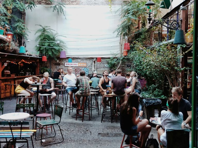Menschen setzen im Innenhof der Kneipe Szimpla Kert, Budapest