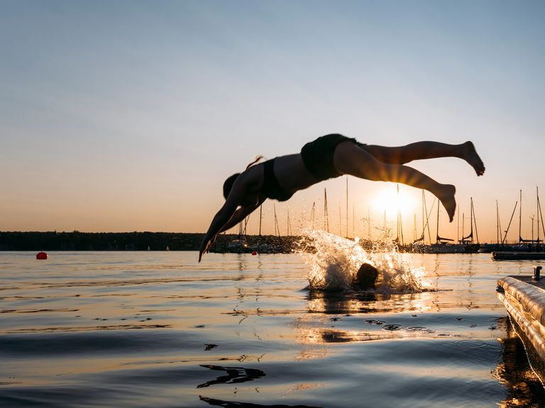 Frau springt bei Sonnenuntergang in den Berliner Wannsee