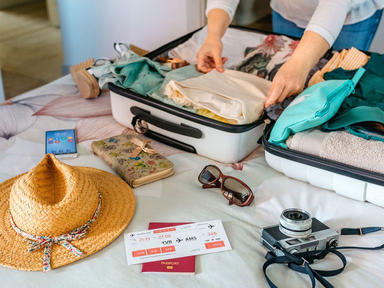 Eine Frau packt einen Koffer für eine Reise