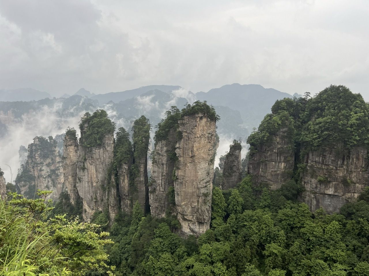 Steile, bewaldete Felsnadeln, umh&uuml;llt von Nebel und tief h&auml;ngenden Wolken