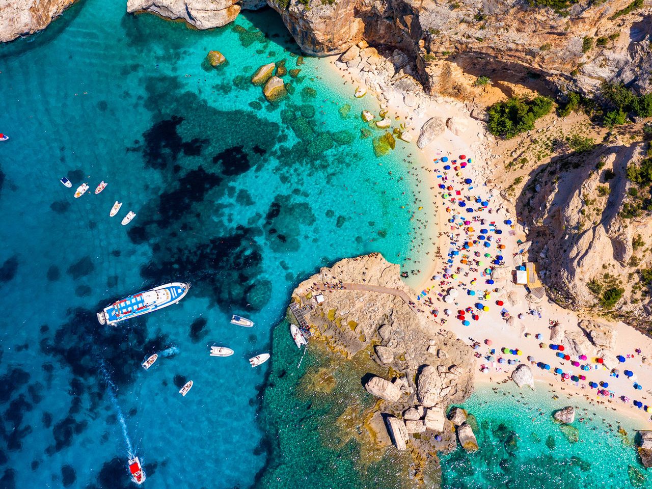 Luftaufnahme von der Cala Mariolu mit Booten und Sonnenschirmen