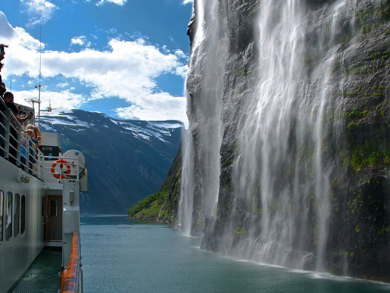 Passagiere beobachten den „Brautschleier“-Wasserfall im Geirangerfjord von Bord eines Schiffes. 