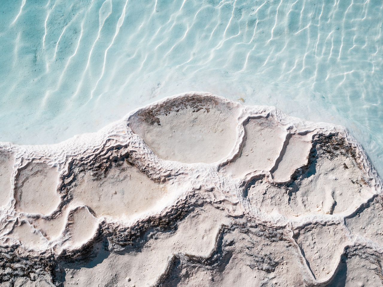 Hellblaues Wasser umschmiegt die Kalkterrassen von Pamukkale