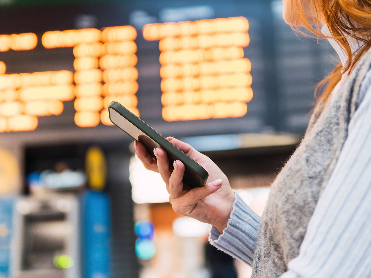 Eine Frau hält am Flughafen ein Smartphone in der Hand