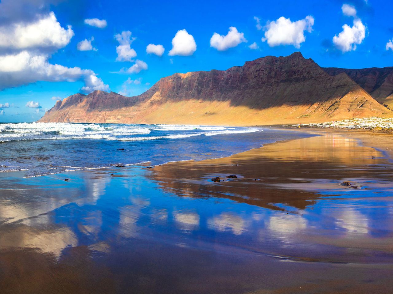 Himmel und Berge spiegeln sich im Wasser an der Playa de Famara, Lanzarote