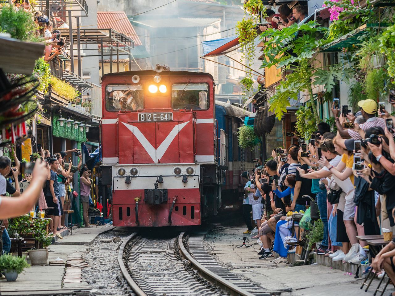 Tourist:innen machen Foto von einfahrendem Zug in der Train Street (Hanoi)