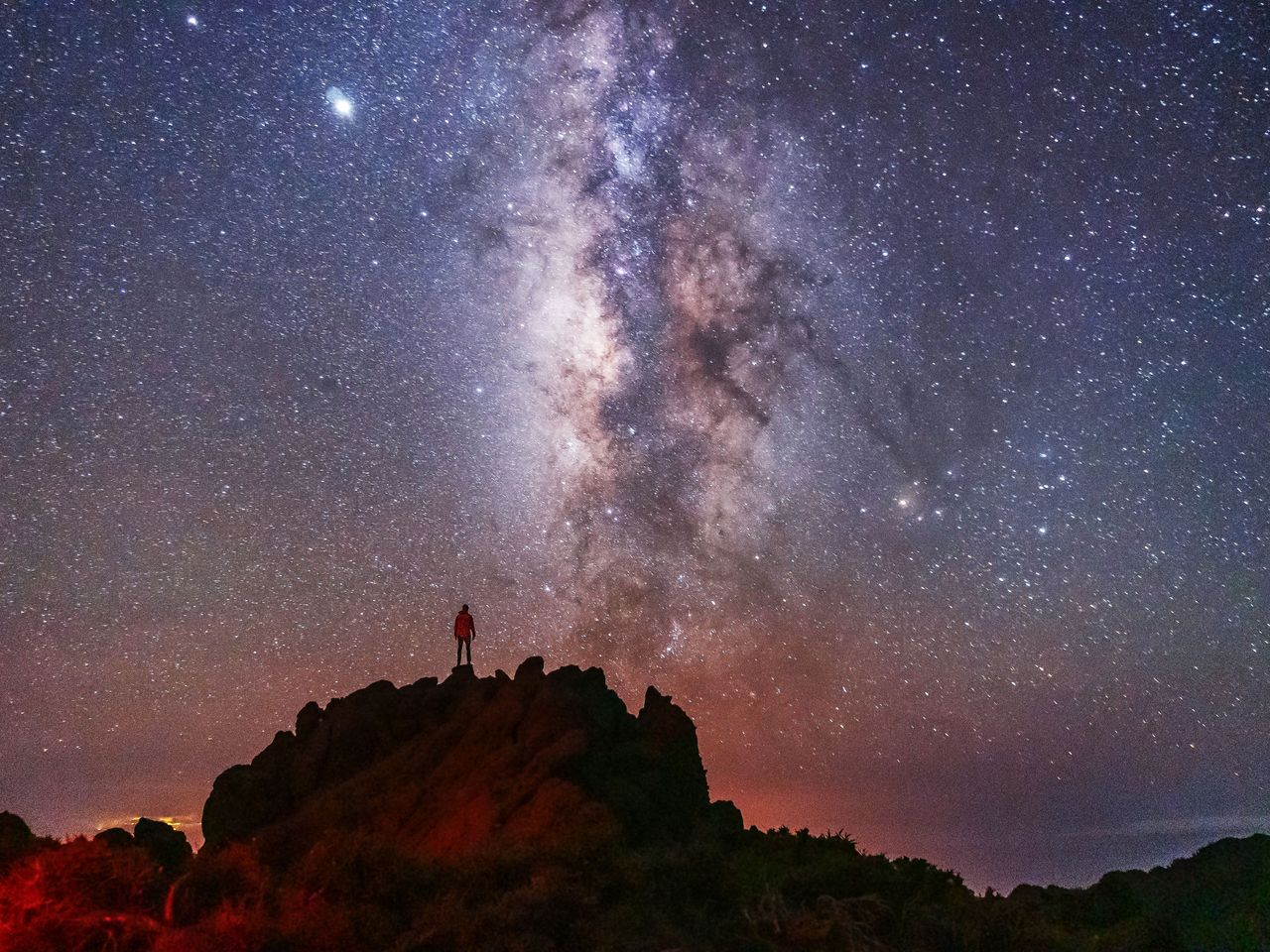 Person steht am Rande der Caldera de Taburiente, La Palma, mit Milchstraße