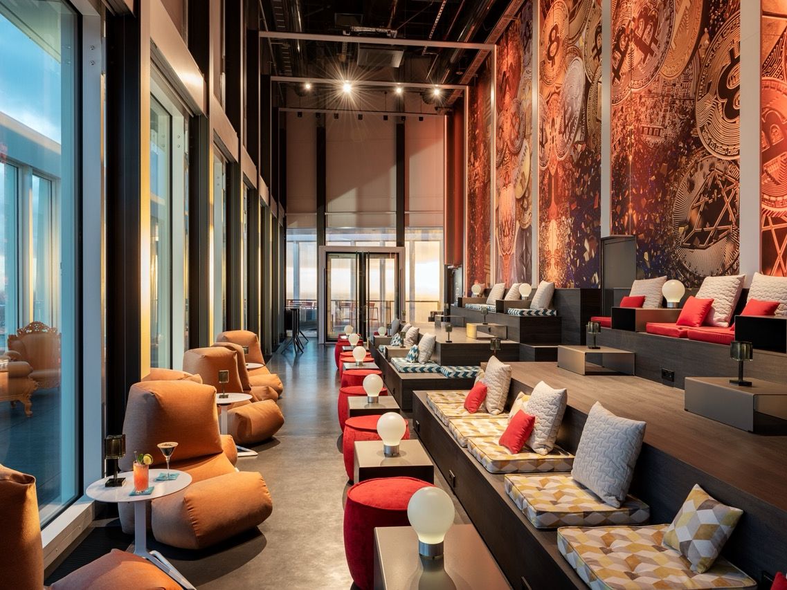 Skybar im nhow Frankfurt mit gro&szlig;en Fensterfronten, Sitznischen, roten Hockern und grafischen Wandmotiven.