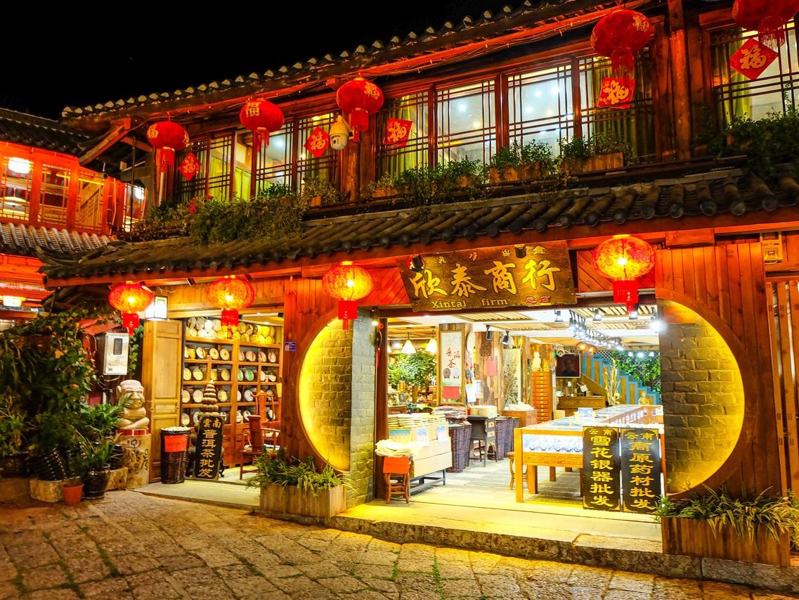 Traditionelles chinesisches Holzhaus mit roten Laternen und rundem Eingang, abends beleuchtet