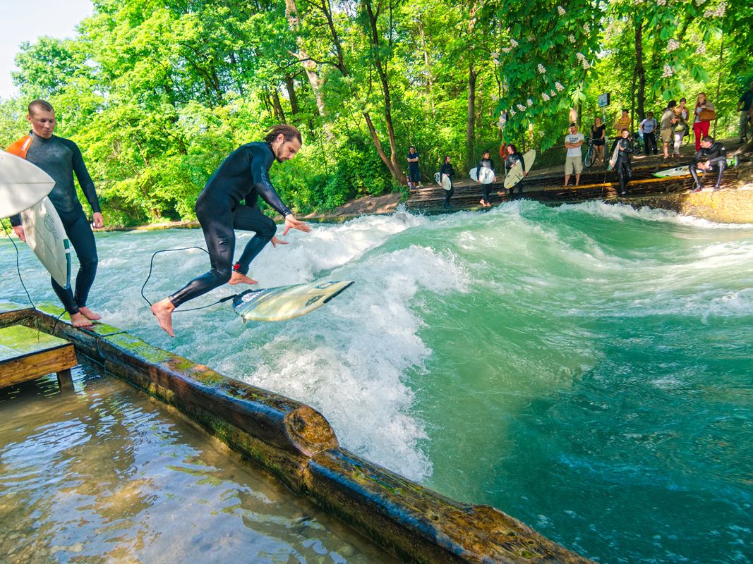 Surfer reiten auf der Eisbachwelle im Englischen Garten