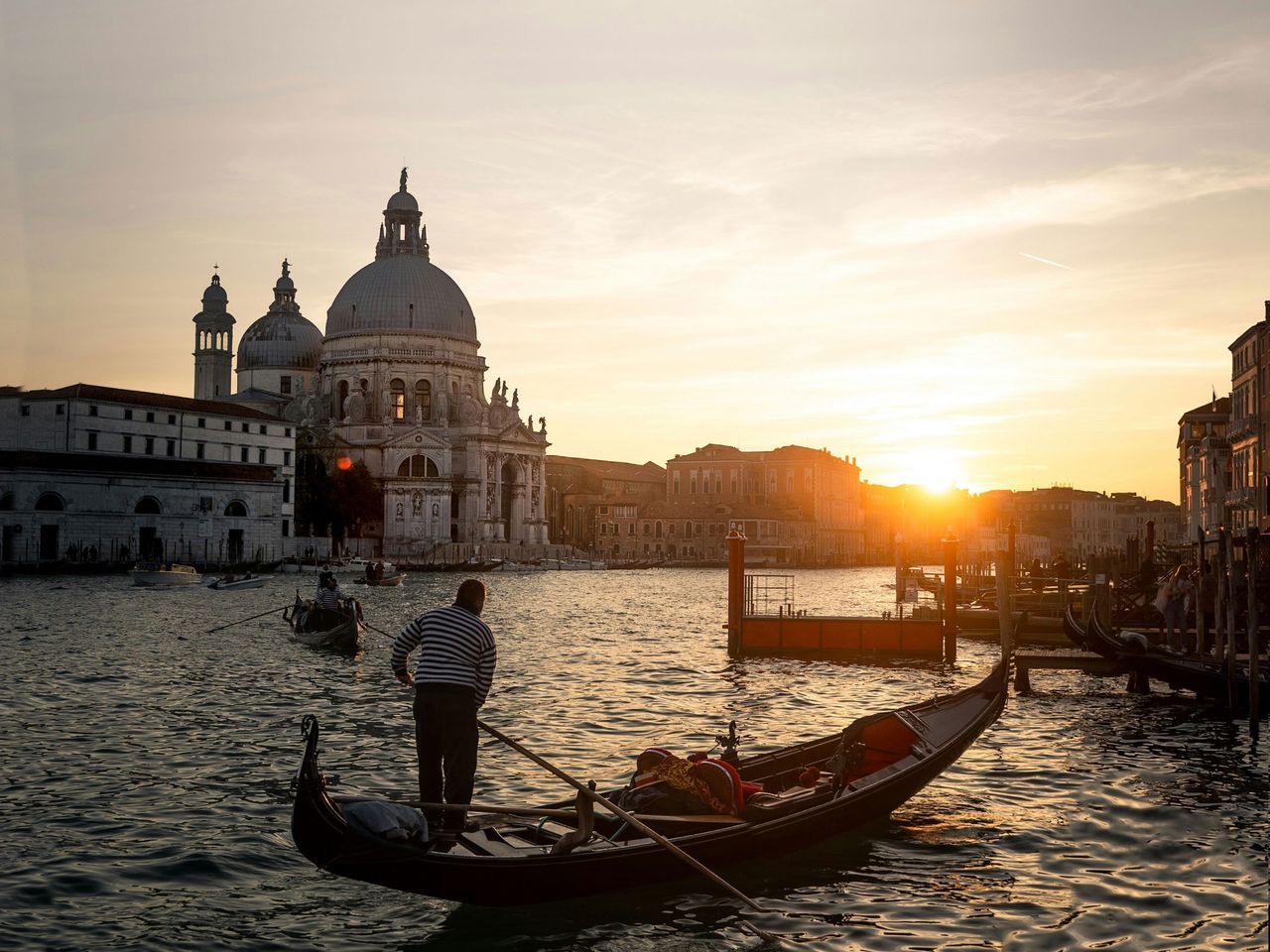 Gondolier auf dem Wasser von Venedig während des Sonnenuntergangs