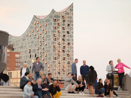 Menschen auf der Hafenpromenade vor der Elbphilharmonie in Hamburg