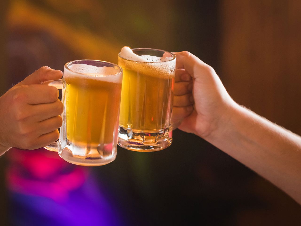 Zwei Personen stoßen mit Bier an