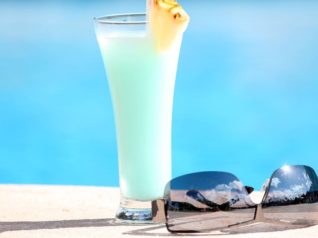 Ein blauer Cocktail ist an einem Pool zu sehen