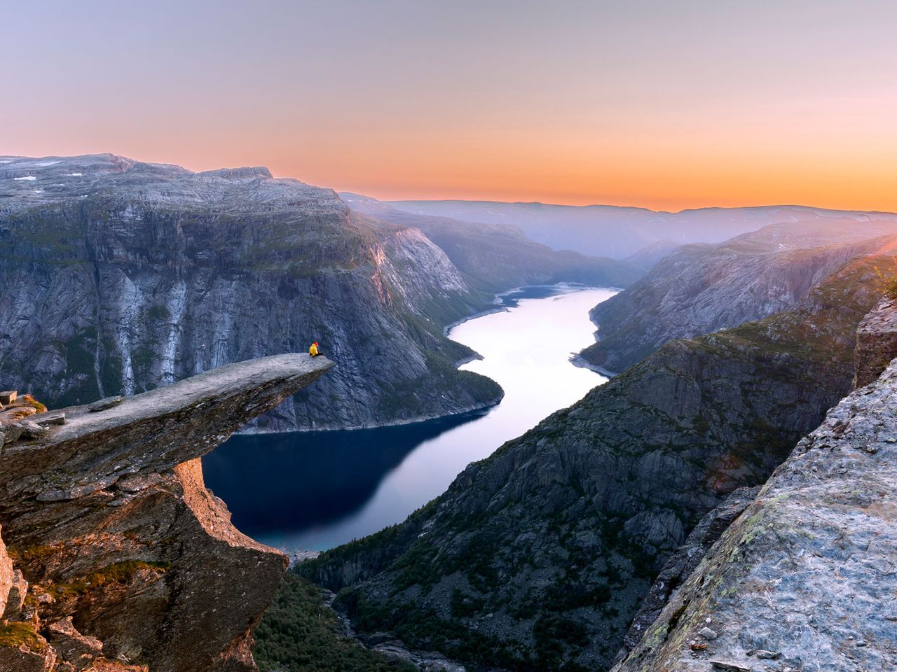 Person sitzt auf der Spitze der Trolltunga, Norwegen