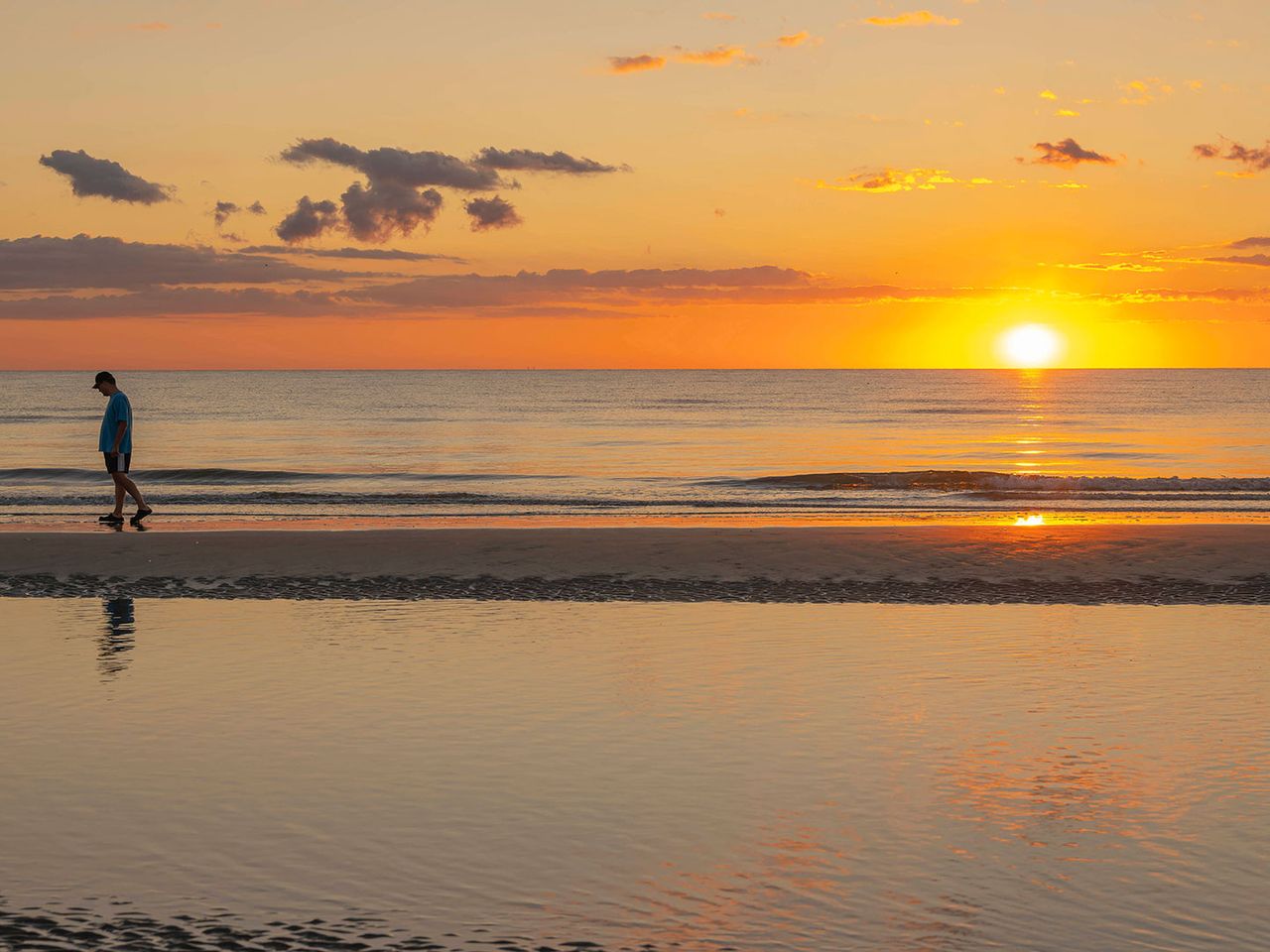 Person geht am Strand von Rømø entlang, Sonnenuntergang im Hintergrund