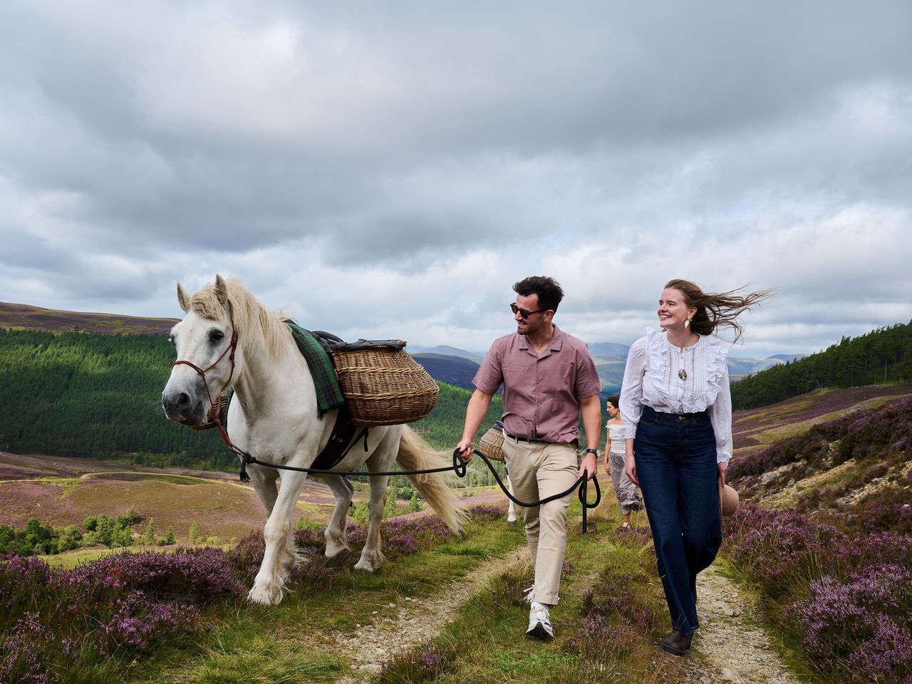 Paar geht mit Pony und Picknickkorb in den schottischen Highlands spazieren