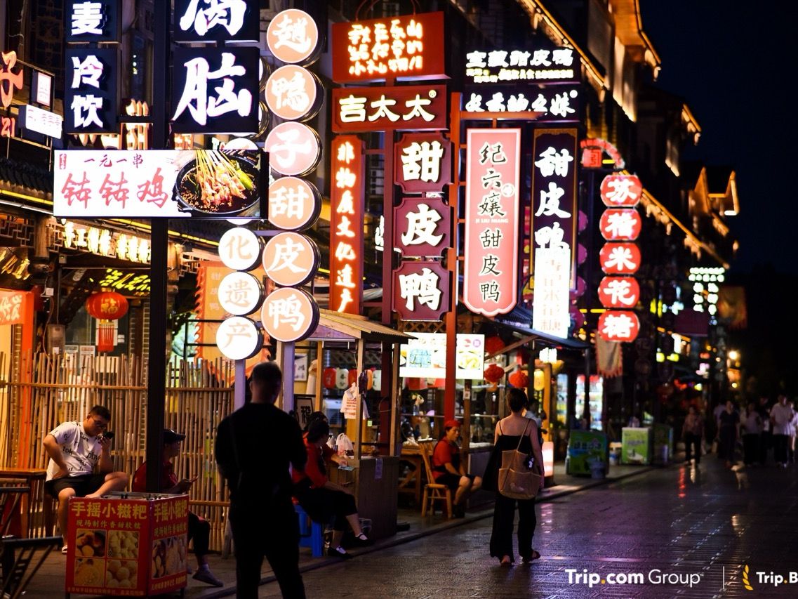 Belebte Einkaufsstraße bei Nacht mit roten Laternen und beleuchteten chinesischen Schriftzeichen